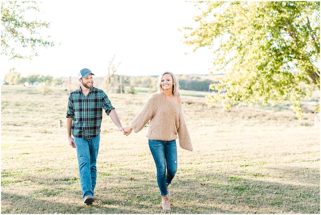 young couple walks together on grass for missouri farm engagement session