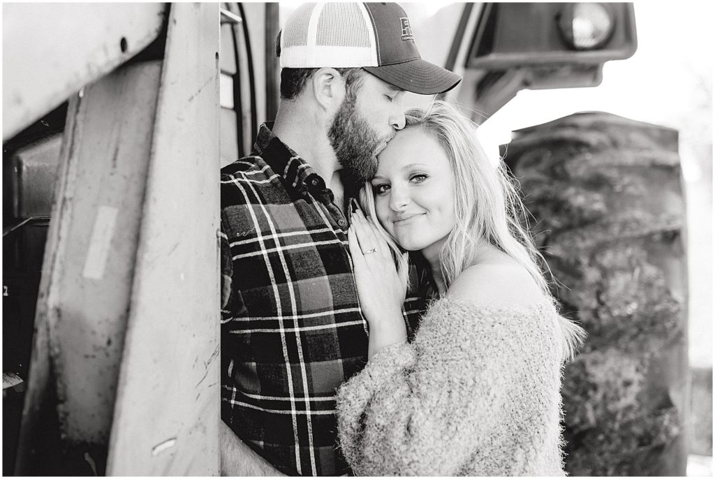 black and white image of couple hugging by tractor during engagement session