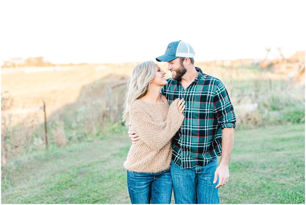 couple walks and kisses wearing sweaters and plaid for pictures