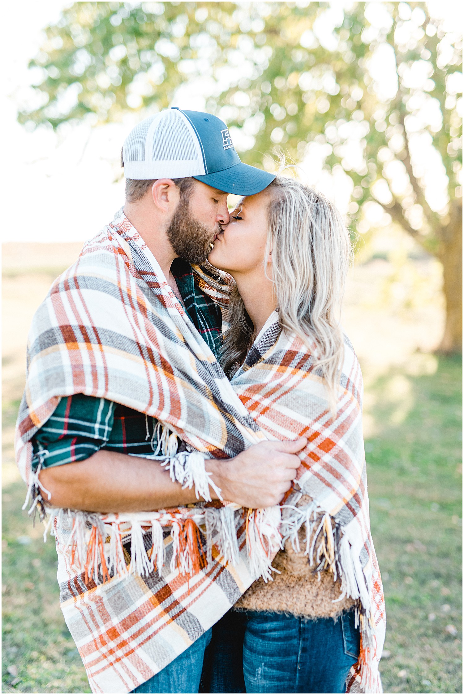 couple kisses each other while wrapped in blanket during engagement session