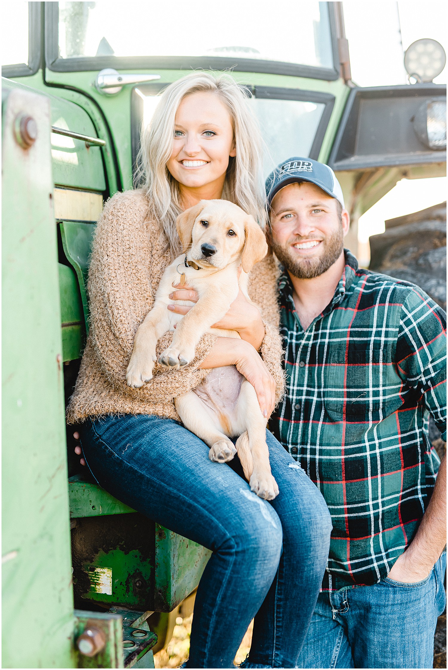 couple holds lab puppy by tractor during engagement session