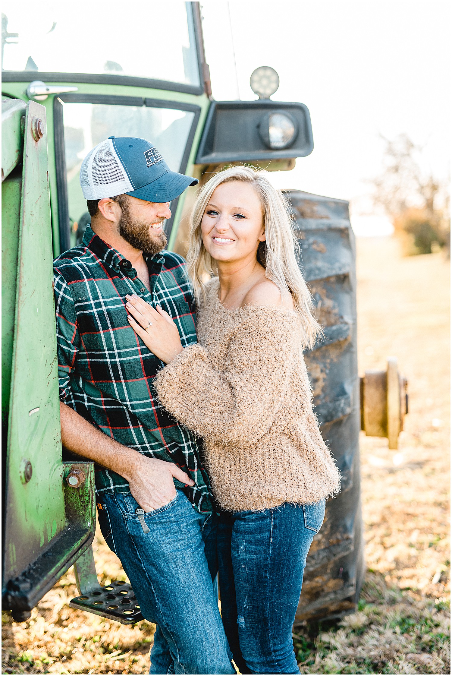 couple laughs with each other standing by tractor during engagement session