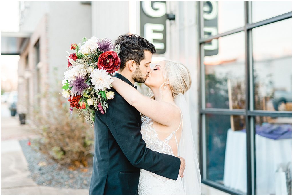 bride and groom kiss outside of wedding venue