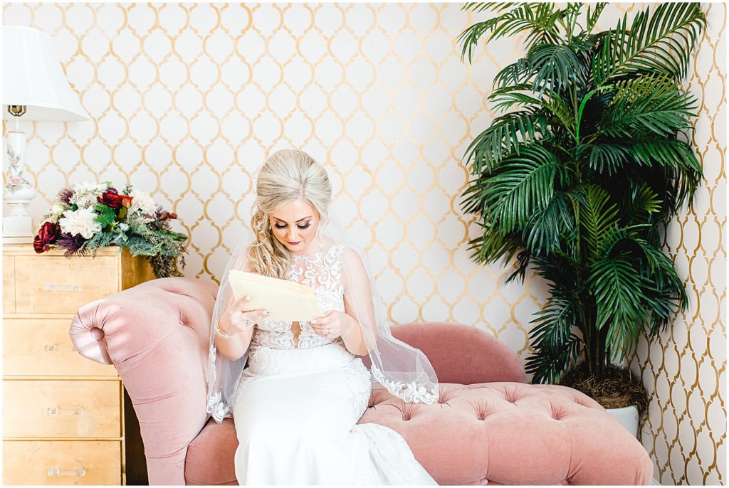bride reads a letter while sitting on a pink couch