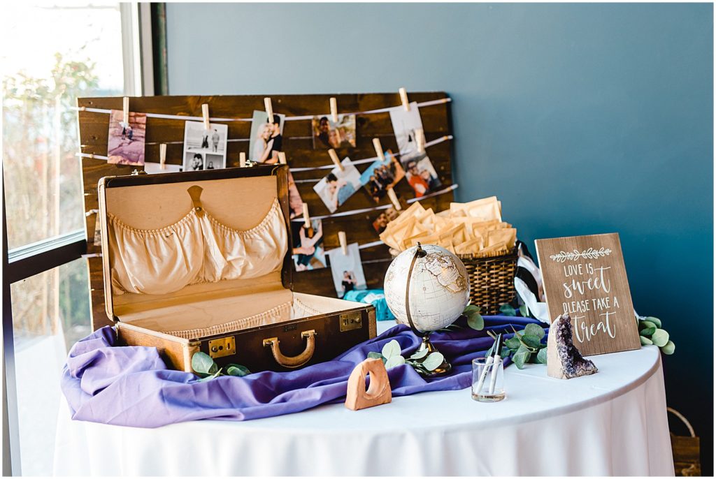 wedding ceremony and reception details welcome table featuring globe and suitcase