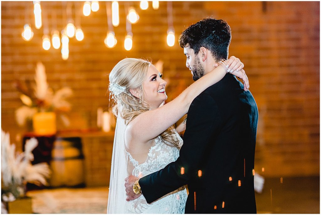 bride and groom smile at each other during first dance at wedding reception