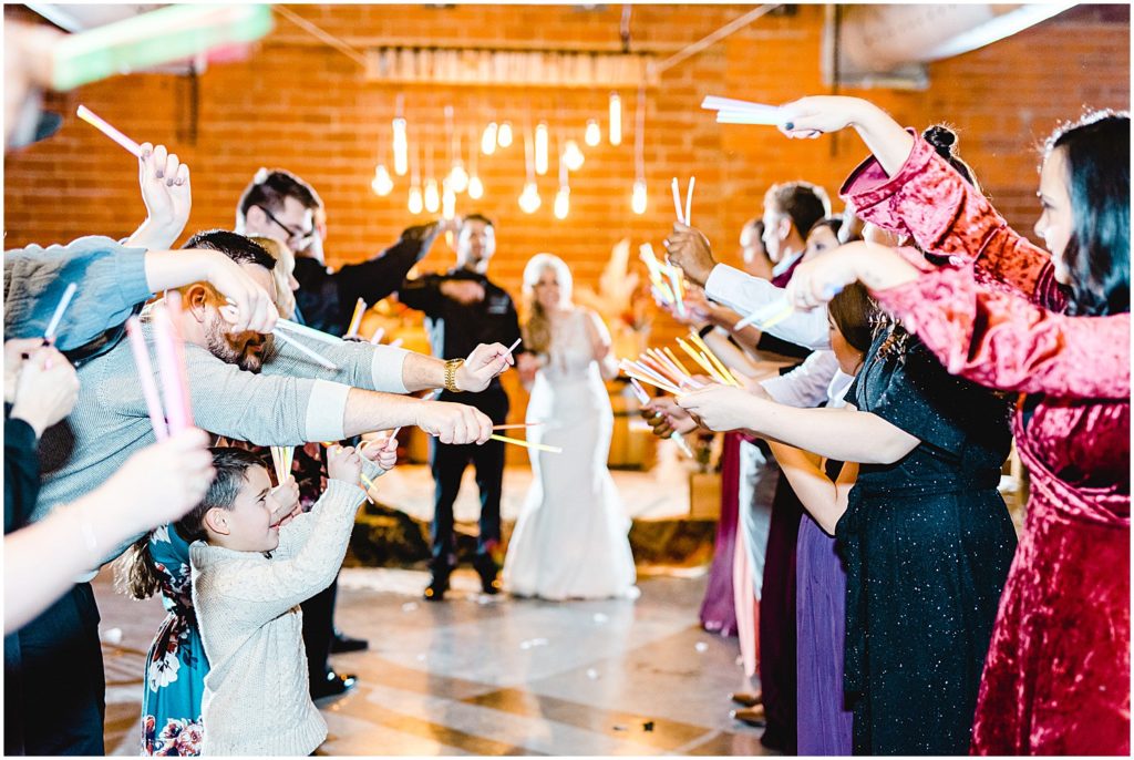wedding guests hold glow sticks during wedding reception at exchange venue
