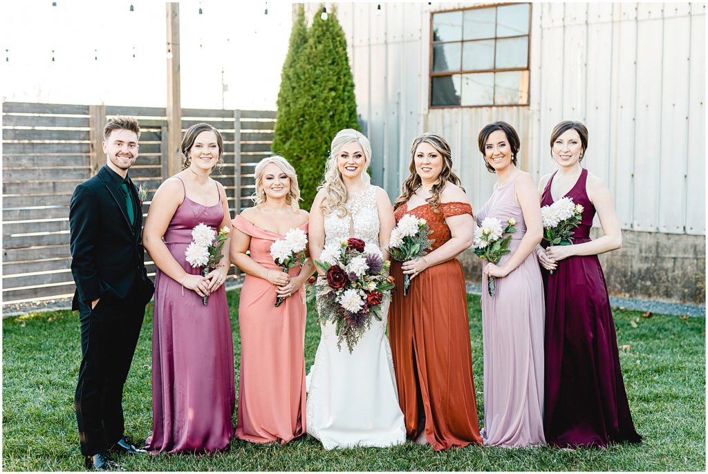 bride and bridesmaids smiling for portrait featuring different colored dresses