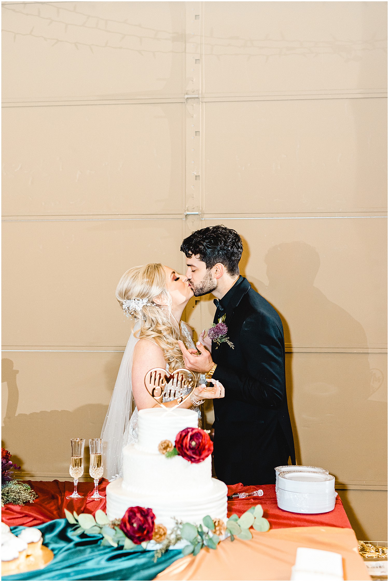 bride and groom kiss after cutting the cake during wedding reception