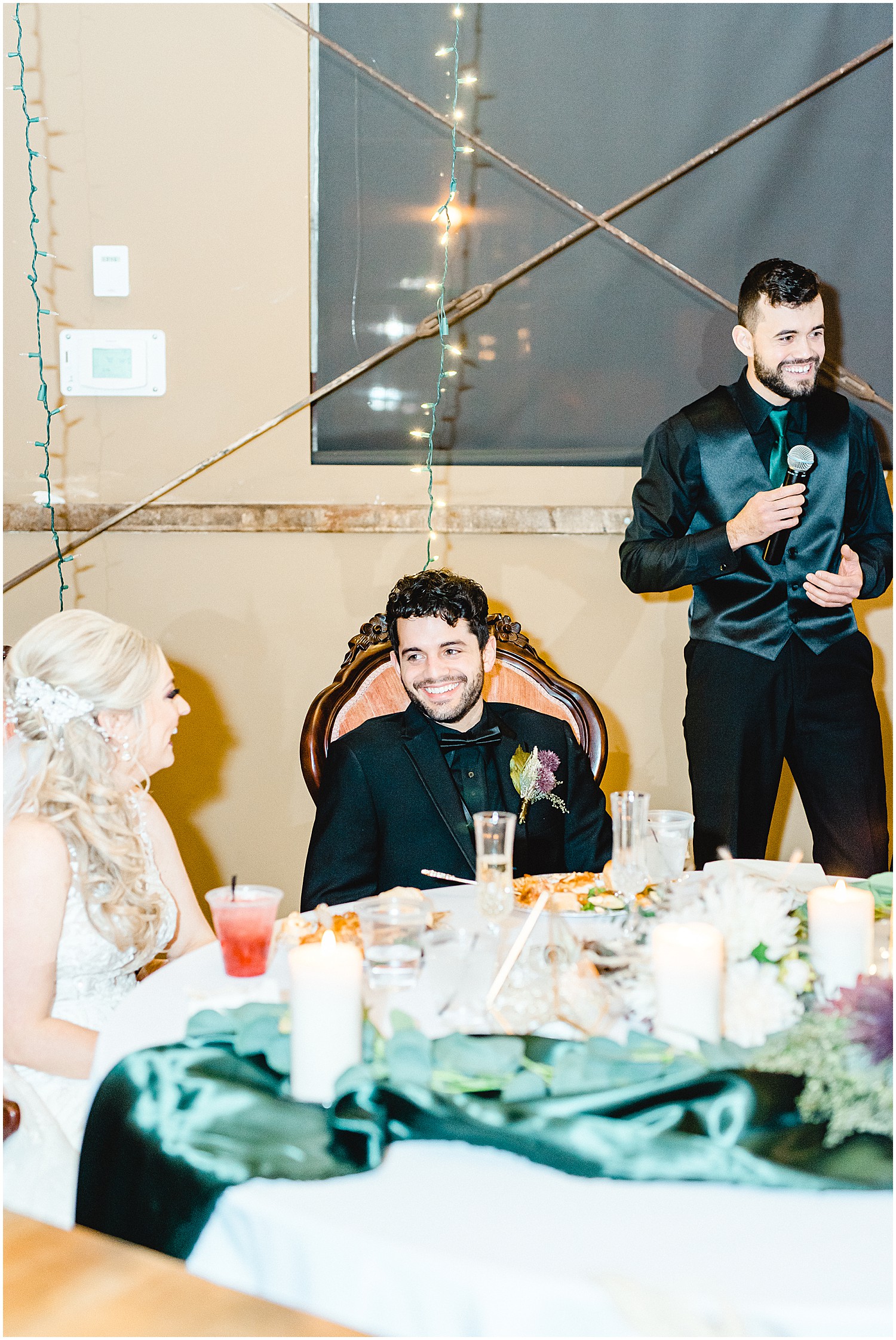 groom smiles as his brother gives a toast during wedding reception