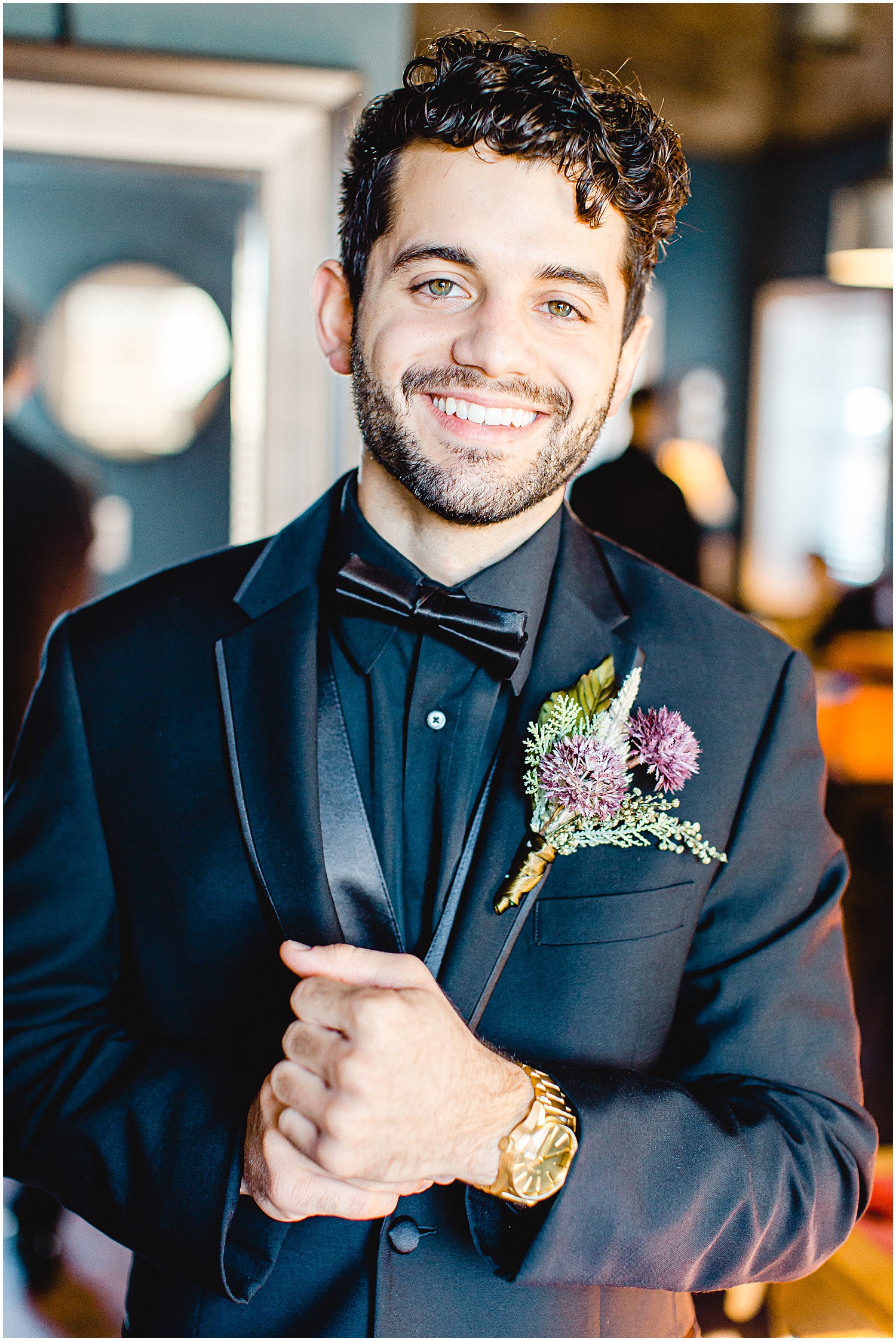 groom smiles at the camera while adjusting watch wearing a black tux