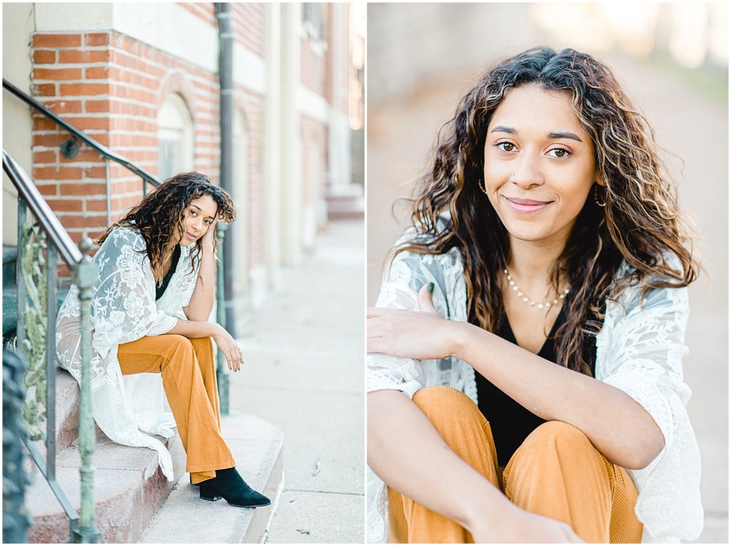 Senior girl wearing yellow pants and long lace cardigan leaning against brick wall in Jefferson City, MO for senior session pictures
