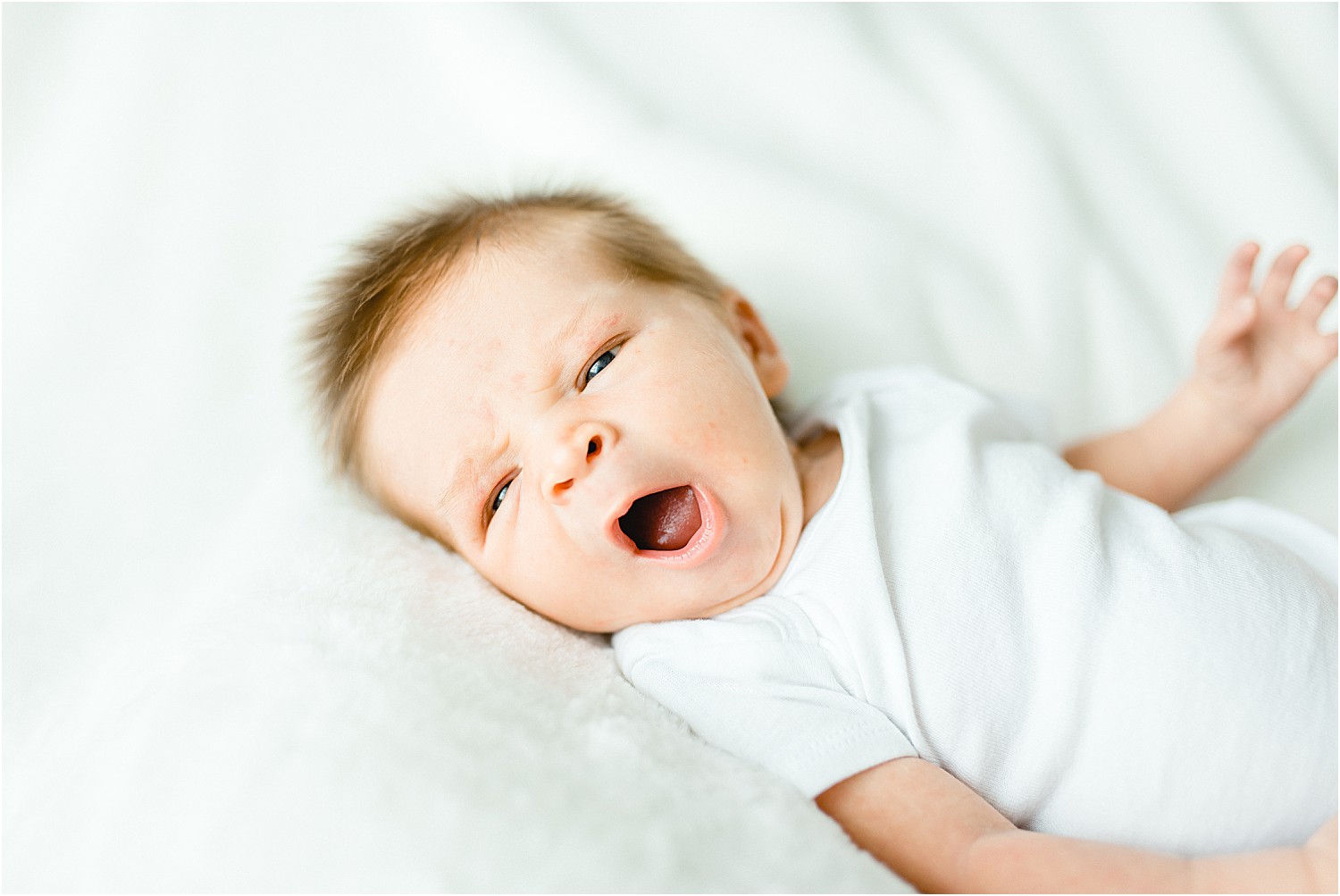 baby boy yawns on white blanket