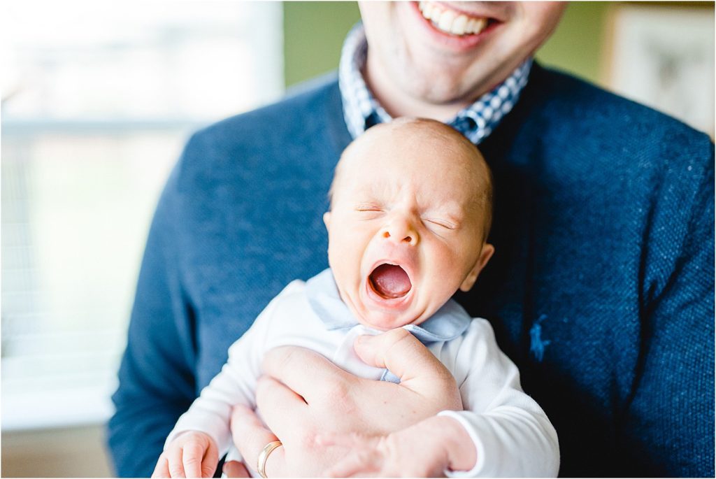 dad holds newborn baby with big yawn