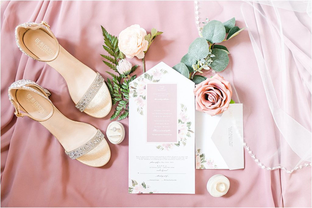 Pink and white wedding day details on a pink fabric background with gold shoes