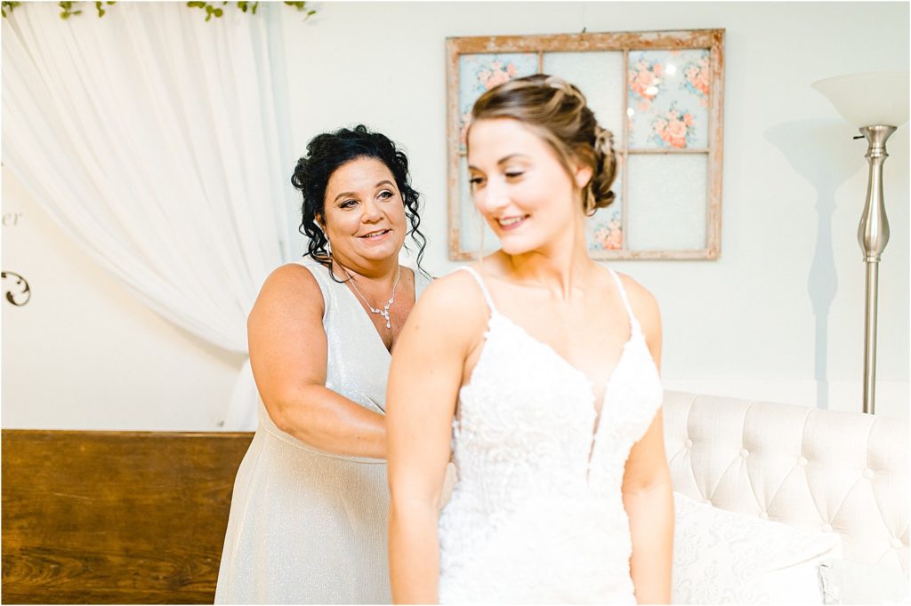 mother helps bride into wedding gown