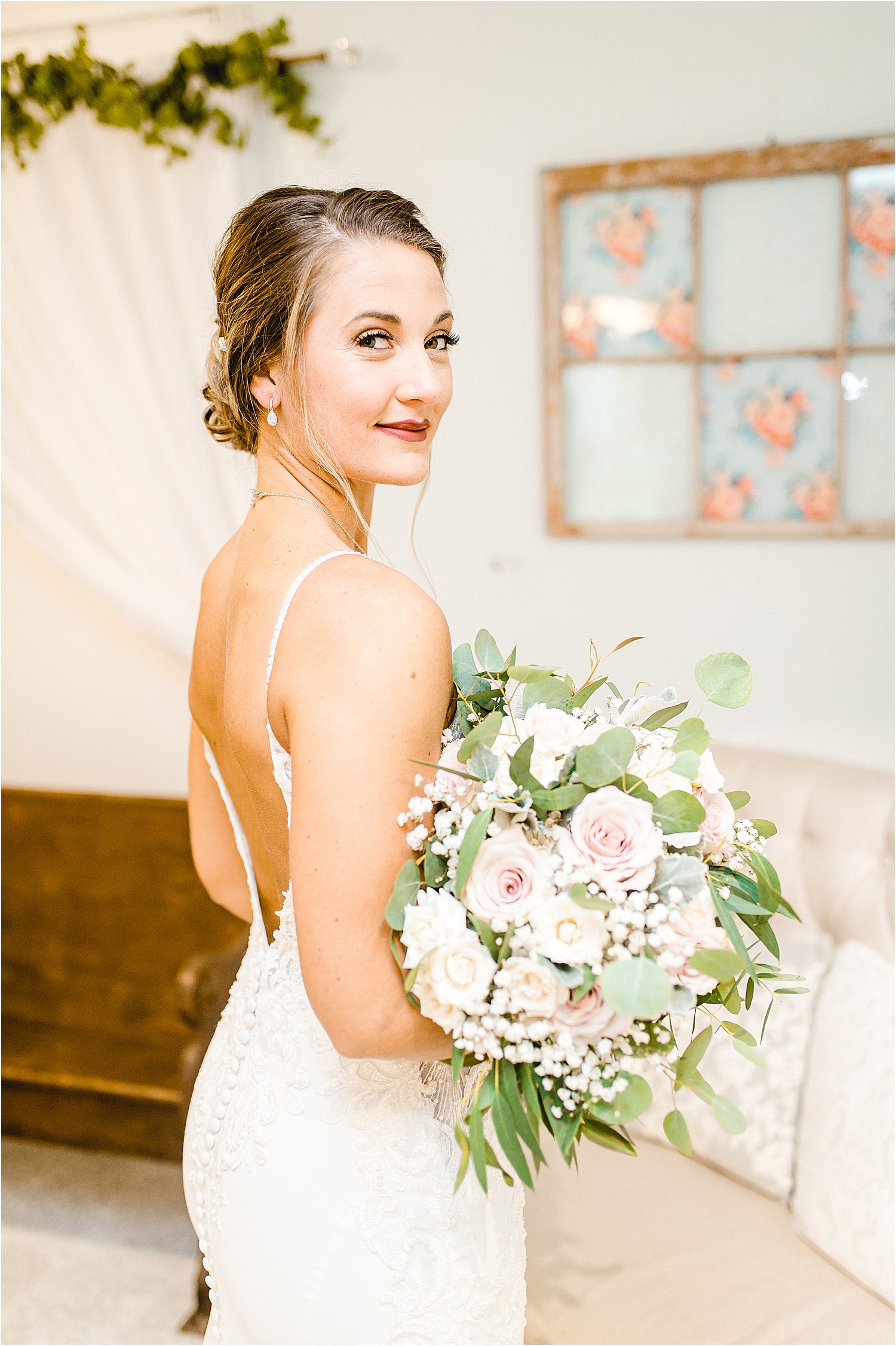 bride looks over shoulder while holding bouquet in wedding dress