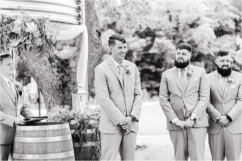 black and white image of groom watching bride during wedding ceremony